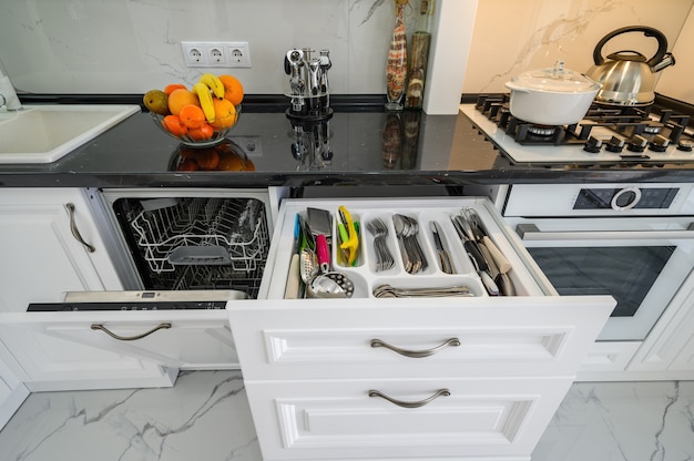 Luxurious white modern kitchen interior drawers pulled out dishwashers door open