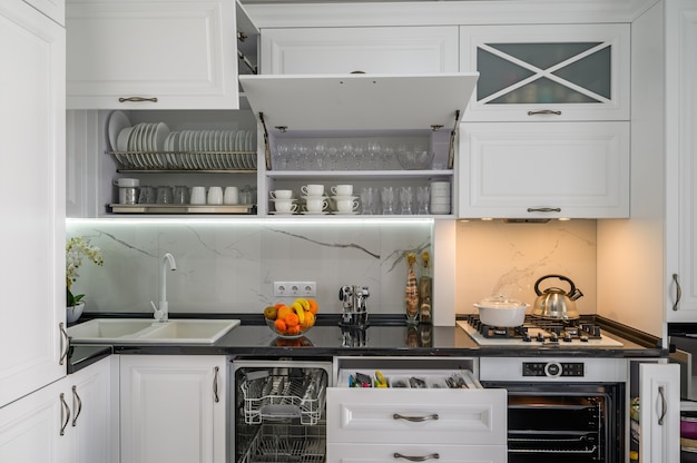 Luxurious white modern kitchen interior drawers pulled out dishwashers door open