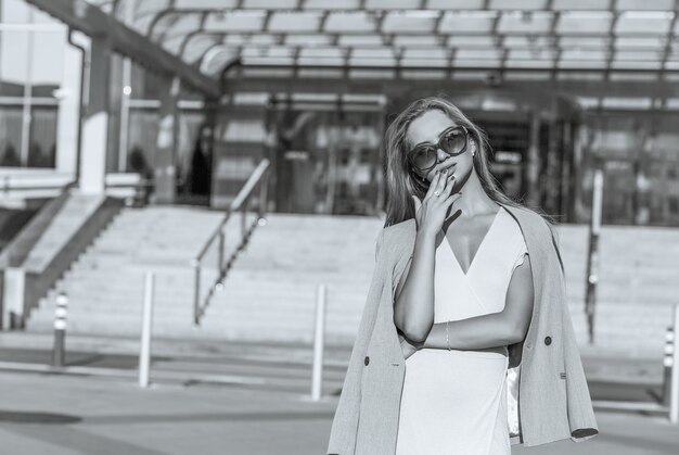 Luxurious young model with long hair wears sunglasses and jacket. Monochrome color. Space for text