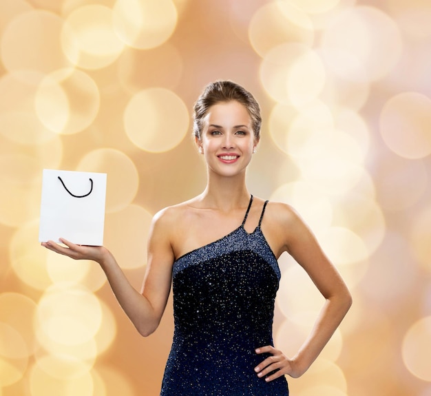 luxury, advertisement, holydays and sale concept - smiling woman with white blank shopping bag over beige lights background
