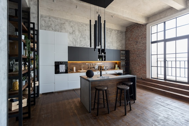 Luxury apartment in a loft style in dark colors. Stylish modern kitchen area with an island