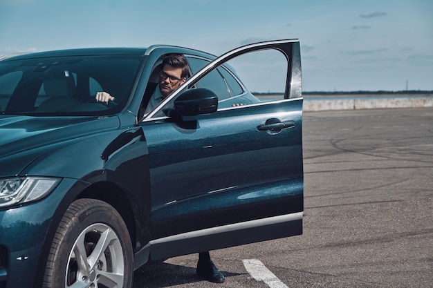 Luxury car. Handsome young man in business wear entering his car