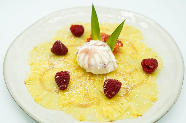 Luxury dessert of pineapple carpaccio with strawberries and cream.