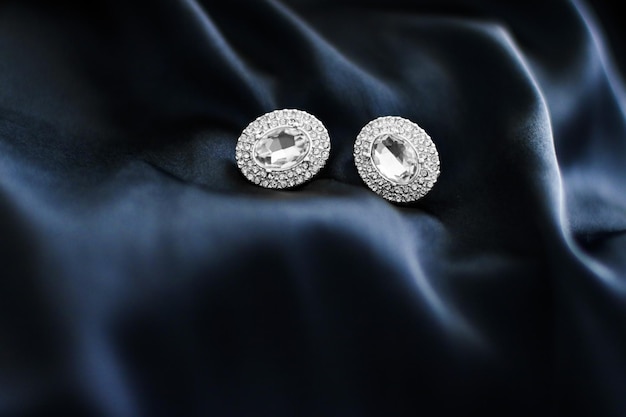 Luxury diamond earrings on dark blue silk background holiday glamour jewelery present