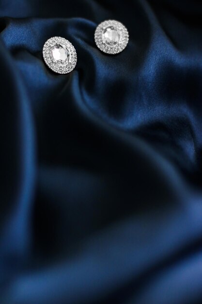 Luxury diamond earrings on dark blue silk background holiday glamour jewelery present