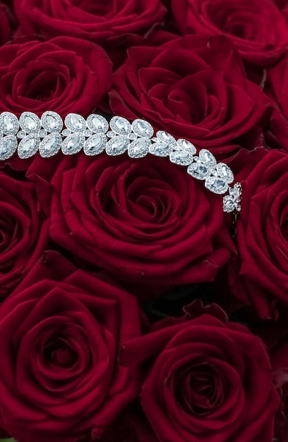 Foto bracciale di gioielli con diamanti di lusso e fiori di rose rosse amano il regalo di san valentino e il design dello sfondo delle vacanze del marchio di gioielli