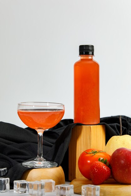 Luxury drink glass and bottle with cool tasty juice beverage from fresh organic fruit of ripe tomato, strawberry and apple flavor. Deluxe nutrition healthy cuisine for celebration party in summer.