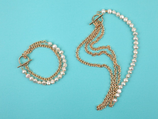 Luxury elegant baroque pearl necklace and bracelet on bright turquoise textured background. Close-up shot