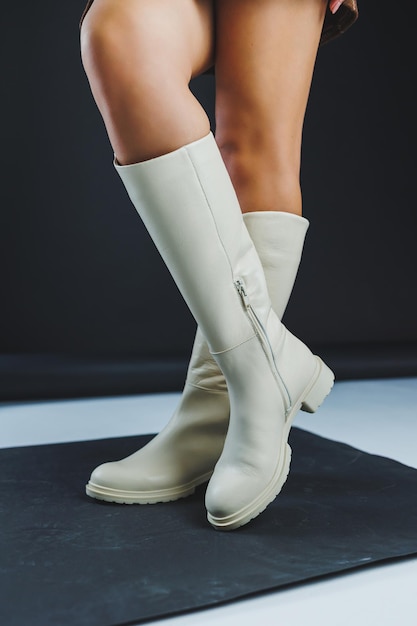 Роскошные элегантные белые женские кожаные сапоги на плоской подошве на женских ногах Коллекция зимней женской кожаной обуви