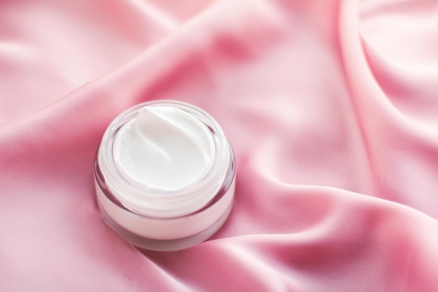 Luxury face cream jar on a soft pink silk