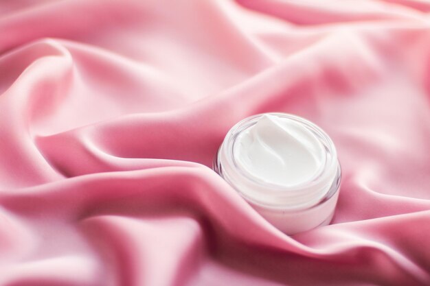 Luxury face cream jar on a soft pink silk