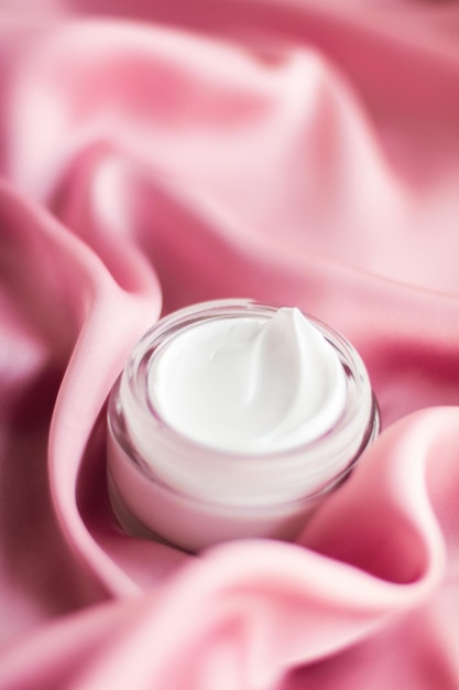 Luxury face cream jar on a soft pink silk