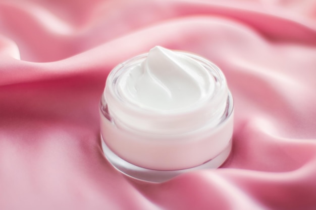 Luxury face cream jar on a soft pink silk