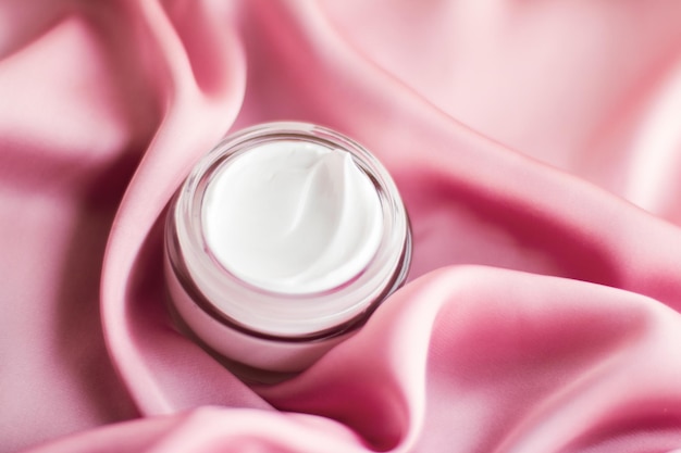 Luxury face cream jar on a soft pink silk