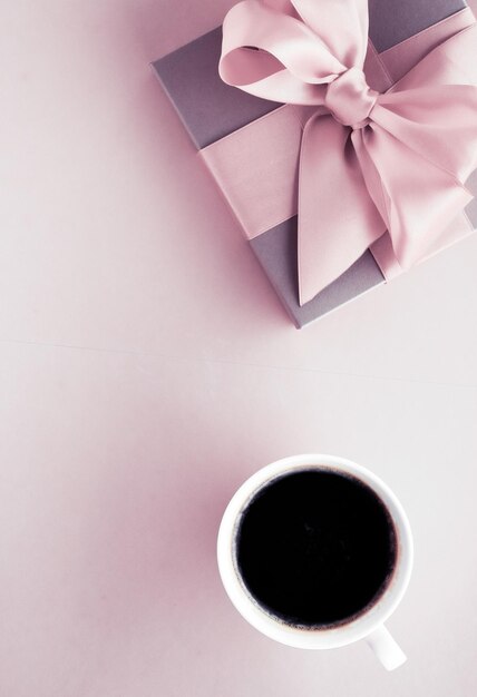 Luxury gift box and coffee cup on blush pink background flatlay design for romantic holiday and birthday surprise