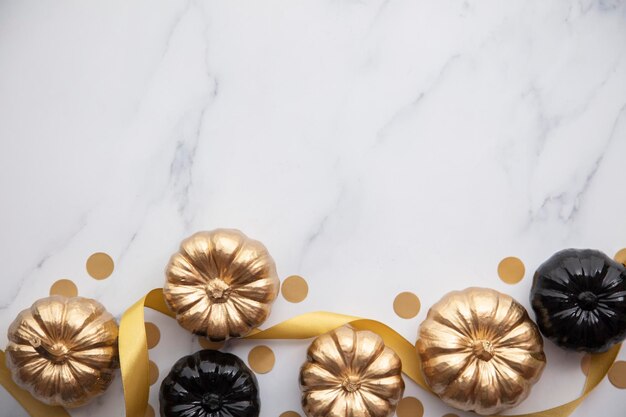 Luxury gold and black autumn pumpkin flat lay composition on a marble background