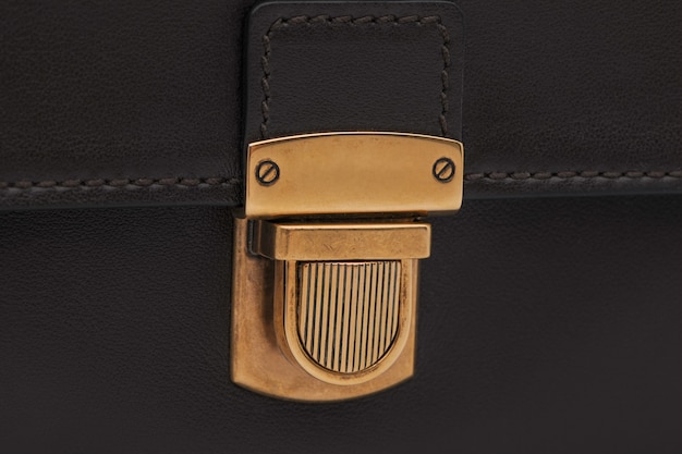 Luxury golden lock clasp on black leather bag, close-up