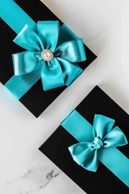 Luxury holiday gifts with emerald silk ribbon and bow on marble background