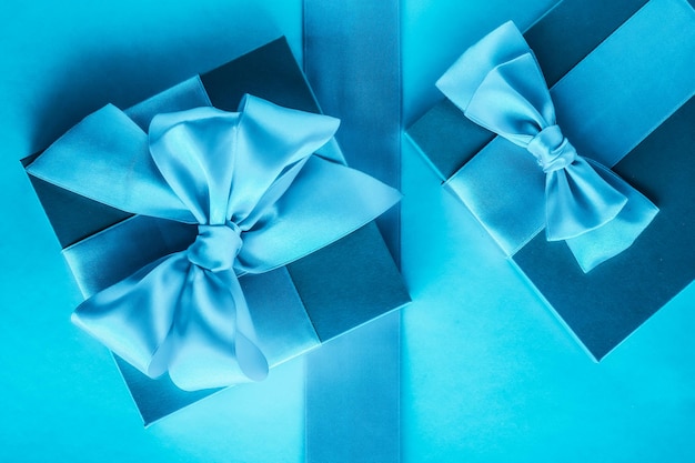 Luxury holiday gifts with silk ribbon and bow on blue background