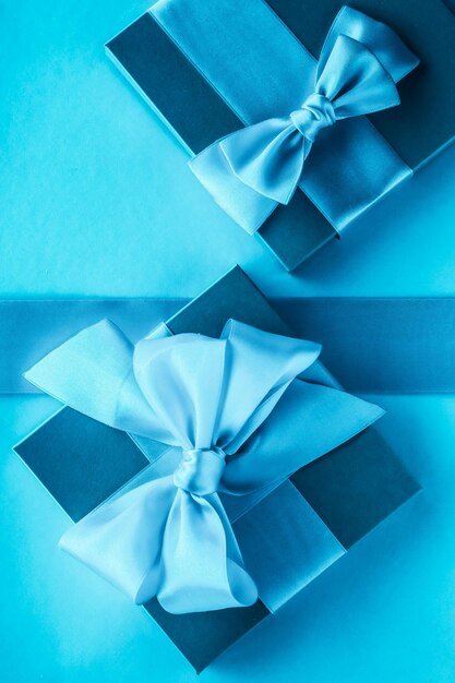 Photo luxury holiday gifts with silk ribbon and bow on blue background