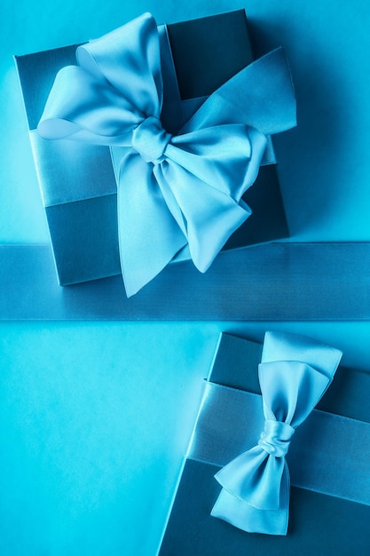 Luxury holiday gifts with silk ribbon and bow on blue background