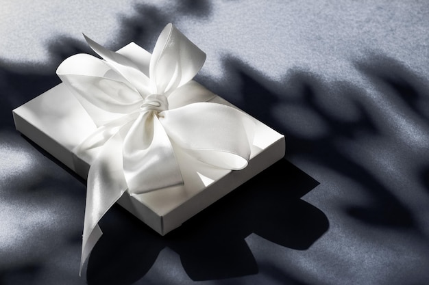 写真 豪華な休日の白いギフト ボックス シルク リボンと黒の背景の豪華な結婚式や誕生日プレゼントに弓