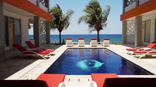 Foto hotel di lusso con piscina, lettini, palme sul mare, resort tropicale con piscina