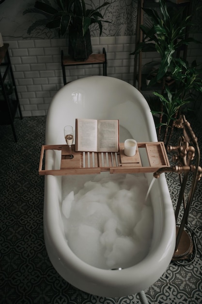 Luxury interior of eco style modern bathroom with oval bathtub and book on bamboo wood tray