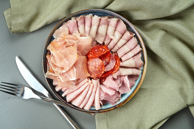 Luxury italian meat antipasti set for wine in ceramic plate on wooden table, top view on salami, ham, prosciutto and chorizo