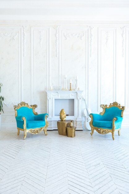 Luxury light interior of living room with gold wall and chic expensive furniture in white and gold colors