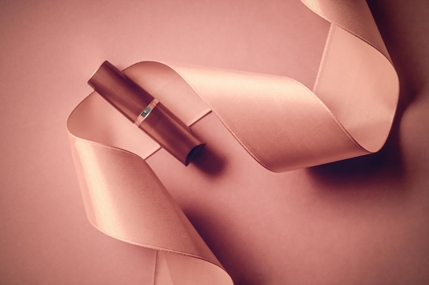 뷰티 브랜드 제품 디자인을 위한 블러쉬 핑크 홀리데이 배경 메이크업과 화장품 플랫레이에 고급 립스틱과 실크 리본