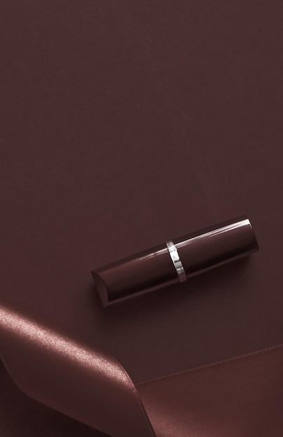 뷰티 브랜드 제품 디자인을 위한 초콜릿 홀리데이 배경 메이크업 및 화장품 플랫레이에 고급 립스틱과 실크 리본