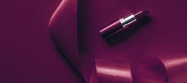 Luxury lipstick and silk ribbon on plum holiday background makeup and cosmetics flatlay for beauty brand product design