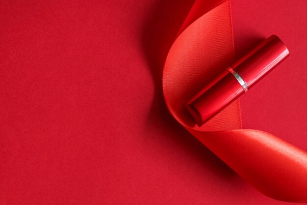 Luxury lipstick and silk ribbon on red holiday background makeup and cosmetics flatlay for beauty brand product design