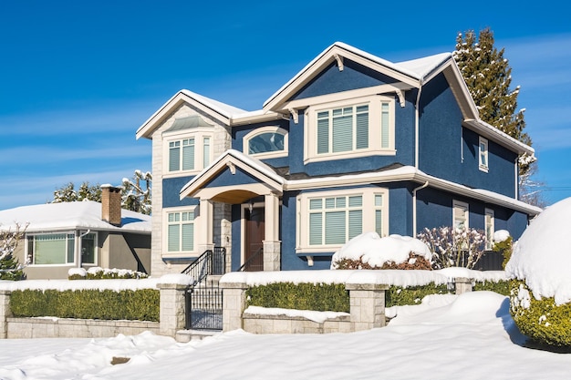 Luxury residential house with front yard in snow on winter sunny day