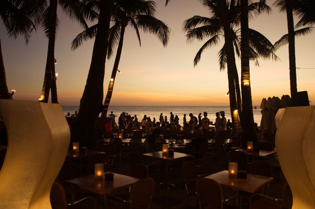 Luxury tropical beach restaurant with people at sunset. Philippines