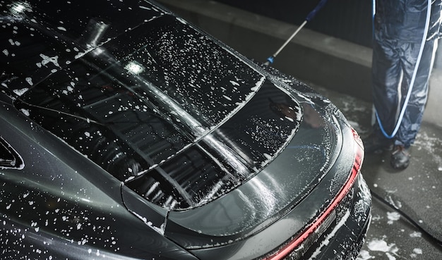 Luxury Vehicle Covered with Water and Powder While Being Pressure Washed at Car Washing Station Care and Maintenance Regular Procedures