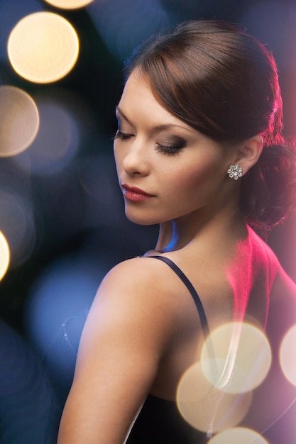 luxury, vip, nightlife, party concept - beautiful woman in evening dress wearing diamond earrings