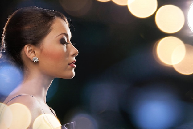 luxury, vip, nightlife, party concept - beautiful woman in evening dress wearing diamond earrings