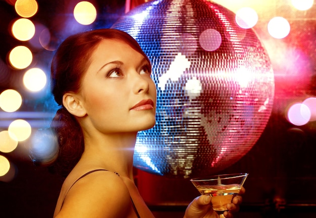 luxury, vip, nightlife, party concept - beautiful woman in evening dress with cocktail and disco ball