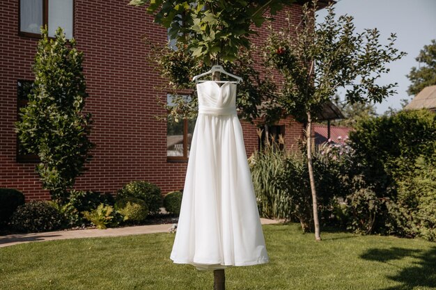 Foto un vestito da sposa di lusso appeso a un filo da bucato su un albero nel giardino