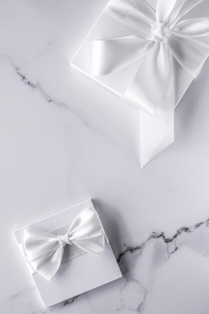 Luxury wedding gifts with silk bow and ribbons on marble background