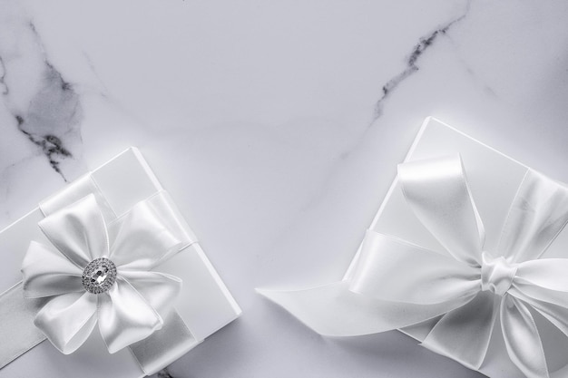 Luxury wedding gifts with silk bow and ribbons on marble background