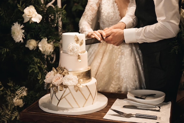 ライトの背景に夜の花の写真で飾られた豪華な結婚式のティアードホワイトケーキ