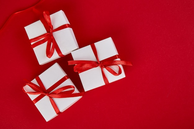 Luxury white gift boxes with red ribbon on red background. Valentine Day, Christmas, birthday party presents. Mother or Woman Day. Flat lay.  Top view.