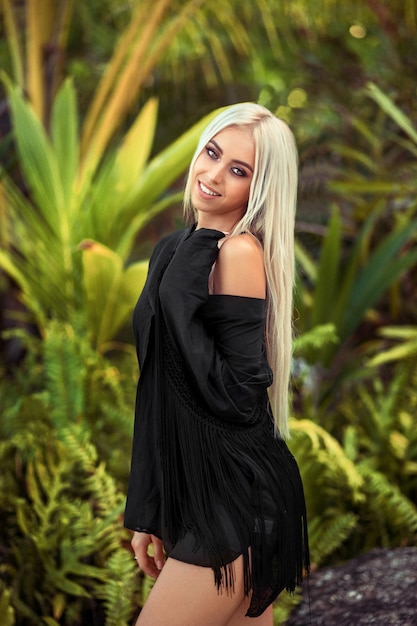 La giovane bionda di lusso in una camicia nera sta sorridendo alla macchina fotografica