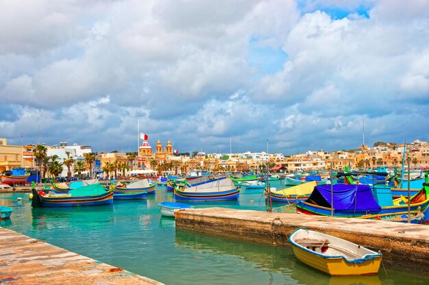 Luzzu colorful boats in Marsaxlokk Port embankment on the bay of the Mediterranean sea, Malta island