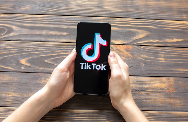 ЛЬВОВ, УКРАИНА - 25 октября 2020 г .: приложение Tik Tok на современном смартфоне. Социальные сети. Деревянный фон.