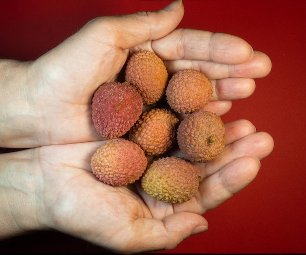Photo lychee on the table chinese plum on a red background ripe fruit from asia delicious juicy product lychee pattern