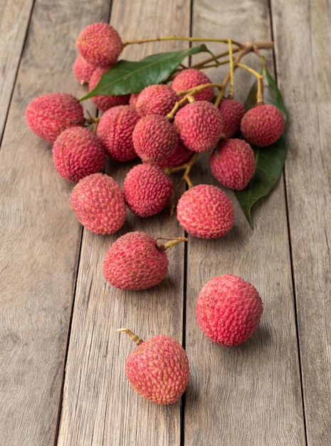 Lychees in branches with leaves over wooden table.